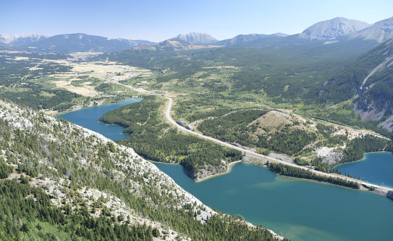 An aerial photo of the entire Crowsnest Pass community, looking out over Crowsnest Lake and a slope of limber pine trees.